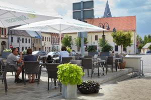 eine Gruppe von Menschen, die an einem Tisch im Freien mit Sonnenschirmen sitzen in der Unterkunft Pension Schlossgasse in Lieberose