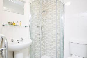 a white bathroom with a shower and a sink at Luccombe Manor Country House Hotel in Shanklin