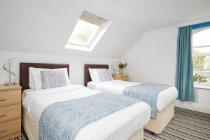 two beds in a white room with a window at Luccombe Manor Country House Hotel in Shanklin
