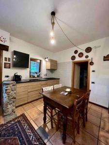 a kitchen with a wooden table with chairs and a television at Chalet Baita Magugnaga in Ceppo Morelli