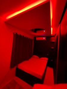 een rode kamer met een bed en een rood licht bij brisas da maré in Passo de Torres