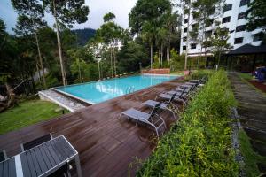 a swimming pool with lounge chairs next to a building at 4-7 Pax Genting View Resort Kempas Residence -Free Wifi, Netflix And Free Parking in Genting Highlands