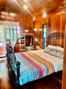 Rang Robin Farmstay with swimming pool في Ban Wang Muang: غرفة نوم بسرير مع جدار خشبي