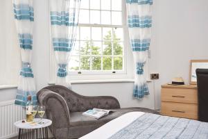 a bedroom with a bed and a chair and a window at Luccombe Manor Country House Hotel in Shanklin