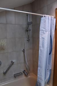 een douche met een wit douchegordijn in de badkamer bij Wohnung Bergtraum inmitten der Ammergauer Alpen in Oberammergau