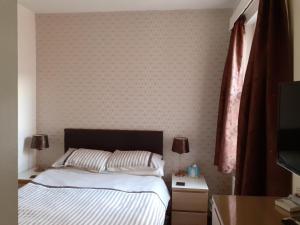 1 dormitorio con cama y pared en Brightwater family room for up to 3 people with shared facilities, en Scarborough