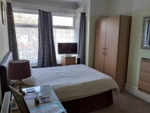 1 dormitorio con 1 cama, TV y ventana en Brightwater family room for up to 3 people with shared facilities, en Scarborough
