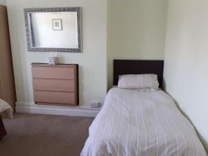 a bedroom with a bed with a dresser and a mirror at Brightwater family room for up to 3 people with shared facilities in Scarborough +8 photos