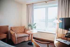 a hotel room with a chair and a window at Hotel & Gastro Adler GmbH in Itzehoe