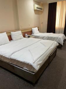 two beds in a hospital room with white sheets at Hotel Zaitona in Erbil