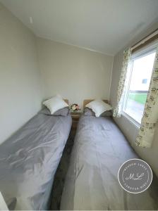 two beds in a room with a window at Palm Grove 181- Golden Palm - Pet friendly, WiFi, central heating, bed linen - Meadow Lakes Caravan & Lodge Hire in Chapel Saint Leonards +9 photos