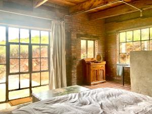 a bedroom with a bed and some windows at Rose Mountain Cottage in Nottingham Road