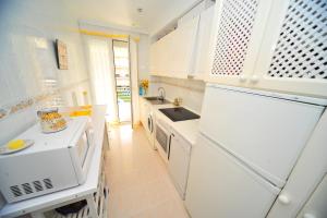 a white kitchen with a sink and a refrigerator at CALA GONZÁLEZ Orange Costa in Alcossebre