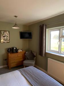 WeobleyMarshpools Bed & Breakfast - Licensed near Weobley village的一间卧室，墙上有一张床和一台电视