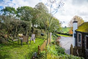 a garden with a table and chairs next to a river at The Stables - Charming 15th-century rural bolthole in Newton Abbot