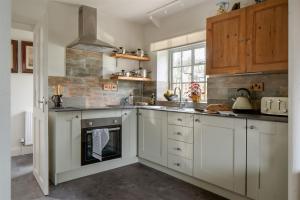 a kitchen with white cabinets and a stove at The Stables - Charming 15th-century rural bolthole in Newton Abbot