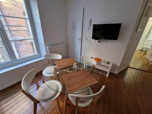 Un comedor con mesa y sillas y un televisor. en Le Voilier, en Dieppe