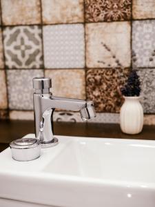un lavandino in bagno con rubinetto e candela di A MI KISHÁZUNK vendégház a Szomód