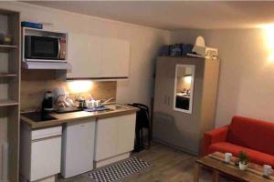 a small kitchen with a red couch in a room at Au bout du bois Piscine sauna hammam accessible en saison et le logement accessible toute l annee in Les Déserts