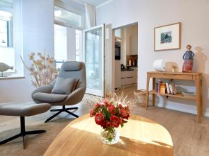 una sala de estar con una silla y una mesa con un jarrón de flores en Ferienwohnung AMAPOLA - Villa Odin en Ostseebad Sellin
