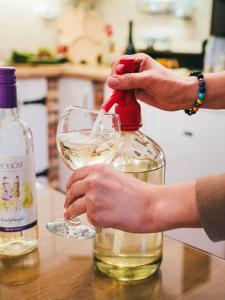 una persona che riempie un bicchiere con una bottiglia di vino di A MI KISHÁZUNK vendégház a Szomód