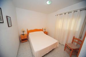 - une chambre avec un lit blanc et une chaise dans l'établissement Las Terrazas - Orange Costa, à Alcossebre