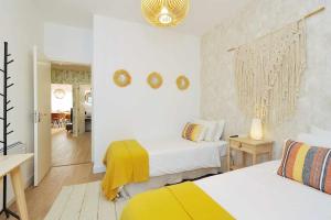 a bedroom with two beds and a yellow blanket at Tropical Pool View Cascais - Checkinhome in Cascais +30 photos