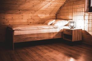 een bed in een houten kamer met een lamp op een tafel bij Dychnij Se in Szczyrk +12 foto's