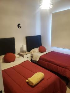 two beds in a room with red and white at La Casita de Lujan in Ciudad Lujan de Cuyo