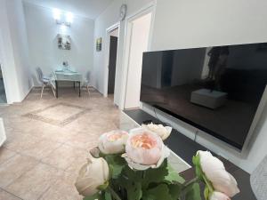 a living room with a television and flowers on a table at eva's villas 2室温馨庭院拥有私家停车位 in Glyka Nera