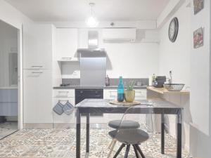 cocina blanca con mesa y barra en Cosy flat proche Gare & Parking - clim, en Agen