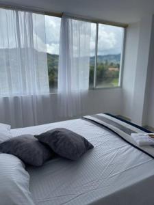 a bed with two pillows in front of a window at Linda casa con espectacular vista embalse y piedra in Guatapé