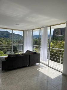 uma sala de estar com um sofá em frente às janelas em Linda casa con espectacular vista embalse y piedra em Guatapé