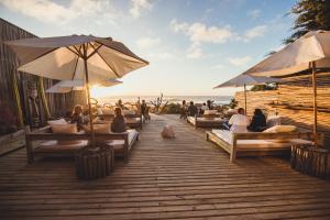 un grupo de personas sentadas en una terraza con sombrillas en Hotel 8 al Mar en Pichilemu