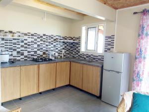 eine Küche mit Holzschränken und einem weißen Kühlschrank in der Unterkunft La Casa Emy in Saint-Leu