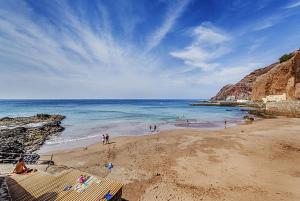 un grupo de personas en una playa cerca del océano en Apartamentos MENBAU, en Gáldar