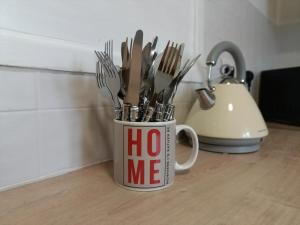 a coffee mug filled with utensils on a table at 2 Bed Functional House Close to Manor Park Train Station in London