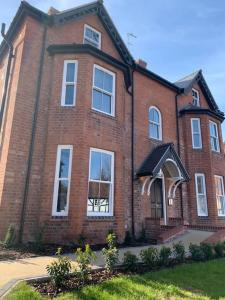 Una gran casa de ladrillo con ventanas blancas en una calle en Boutique Luxury Apartment, High St, Henley-in-Arden en Henley in Arden