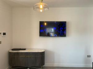 a room with a table and a tv on a wall at Boutique Luxury Apartment, High St, Henley-in-Arden in Henley in Arden