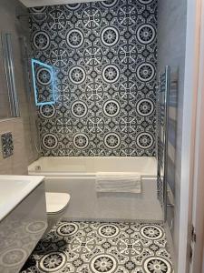 a bathroom with a shower and a toilet and a tile wall at Boutique Luxury Apartment, High St, Henley-in-Arden in Henley in Arden