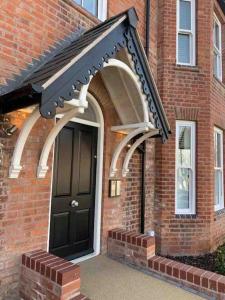 a black front door of a brick house at Boutique Luxury Apartment, High St, Henley-in-Arden in Henley in Arden