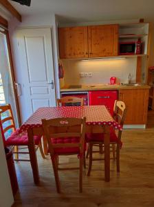 a kitchen with a table and chairs and a red kitchen at Les Arolles E23, classé 3 étoiles à Chamrousse 1700 in Chamrousse