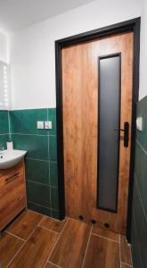 a bathroom with a wooden door and a sink at WOKU Studio - apartament in Świebodzice