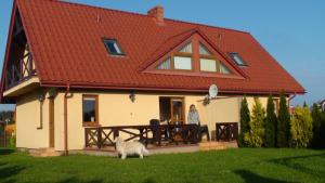 a woman standing in front of a house with a dog at Rowy, Słoneczne plaże in Rowy