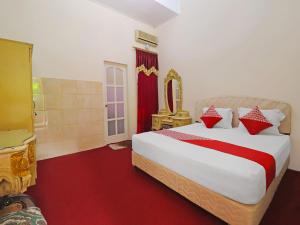 ein Schlafzimmer mit einem großen Bett mit roten und weißen Kissen in der Unterkunft OYO 2899 Ardilia Bandara Syariah in Jambi