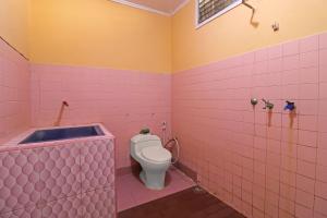 a pink bathroom with a toilet and a bath tub at OYO 2899 Ardilia Bandara Syariah in Jambi