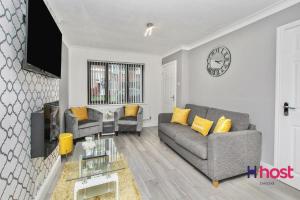 a living room with a couch and a clock on the wall at Host Liverpool - Cosy Family Home, Parking, Liverpool in West Derby