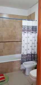 y baño con aseo y cortina de ducha. en Departamento céntrico en Villa Carlos Paz