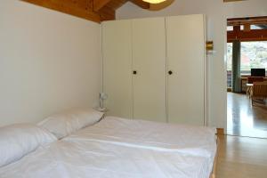 a bedroom with a bed with white sheets and cabinets at Seewohnung 1 in Spiez