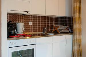 a kitchen with white cabinets and a sink at Seewohnung 1 in Spiez